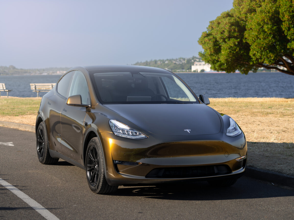 A gold color-shift wrapped Tesla Model Y at golden hour, wrapped at SeaWraps