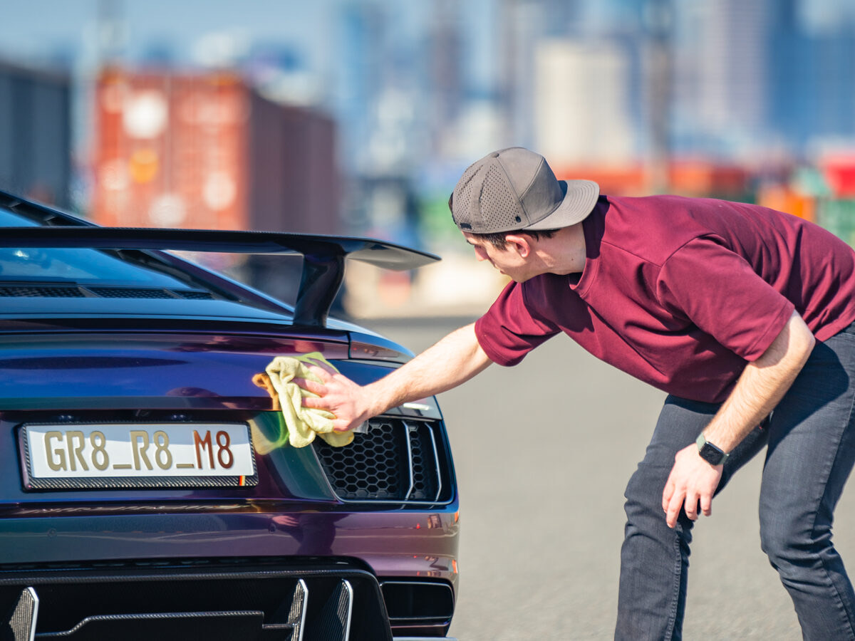 An installer hand-polishing the rear of a purple Audi R8 at SeaWraps